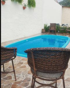 a swimming pool with two chairs and a table at Pousada Vitória in Penha