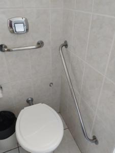 La salle de bains est pourvue de toilettes blanches et d'une balustrade pour personnes à mobilité réduite. dans l'établissement Hotel Caverá, à Alegrete