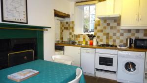 a kitchen with a table and a stove top oven at Cherry Cottage, Youlgrave Nr Bakewell in Youlgreave