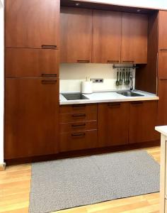 a kitchen with wooden cabinets and a sink and a rug at Piso ideal en Goya junto a Wizink Center in Madrid