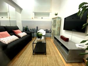 sala de estar con sofá negro y TV de pantalla plana en Piso ideal en Goya junto a Wizink Center, en Madrid