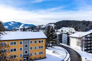 an apartment building in the snow with mountains in the background at Imbergblick in Oberstaufen