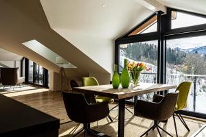 une salle à manger avec une table, des chaises et une grande fenêtre dans l'établissement Alpenloft Ausblick, à Oberstaufen