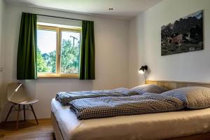 a bedroom with a bed with green curtains and a window at Lohansler Hütte in Oberstaufen