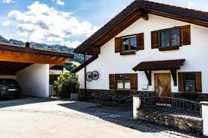 ein weißes Haus mit Holzfenstern und einer Auffahrt in der Unterkunft Himmelseck in Oberstaufen