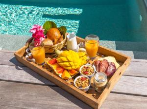 een dienblad met eten en drinken naast een zwembad bij Karibuni Boutique Hotel in Cul de Sac