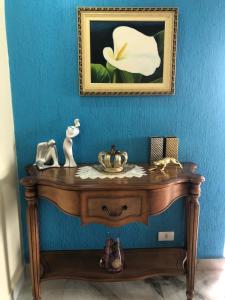 Una mesa de madera con una pintura de una flor en una pared azul. en Apto Azul Oceano, en Mongaguá