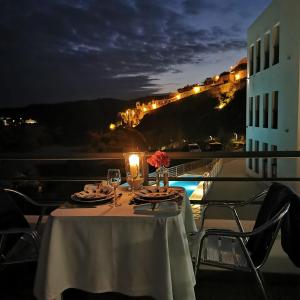 a table with wine glasses and flowers on a balcony at night at Hotel Museu in Mértola
