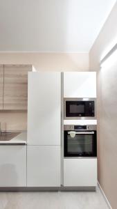 Fiera Milano City Apartment في ميلانو: مطبخ مع دواليب بيضاء وميكرويف