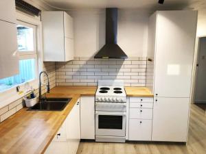 cocina blanca con fogones y fregadero en Few Steps Into Town - Corner House en Geraldton