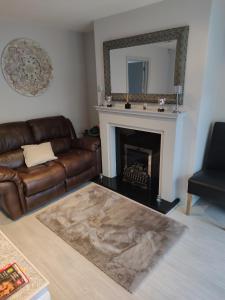 a living room with a leather couch and a fireplace at Lewis Square Town House in Belfast