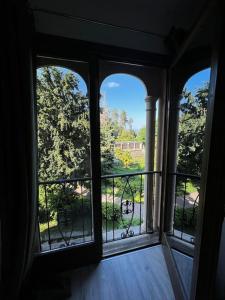 a room with three windows and a balcony with trees at Appartamento in Villa Storica in Oleggio Castello