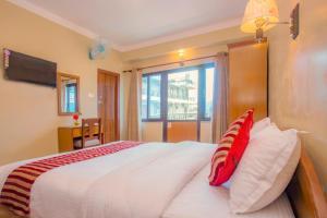1 dormitorio con 1 cama grande con almohadas rojas y blancas en Hotel Liberty Pokhara en Pokhara