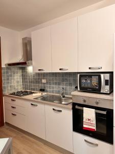 a kitchen with white cabinets and a sink and a microwave at Holidays Apartment in Cagliari