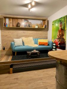 ein Wohnzimmer mit einem blauen Sofa und einem Tisch in der Unterkunft Die Pilgerbox, Tiny House trifft Urlaub in Dahlem