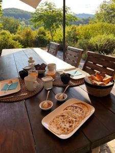 una mesa de madera con comida y pan. en La Parenthèse du Var - Chambre d'hôtes petits déjeuners inclus et terrasse ombragée, en Saint Antonin du Var