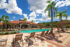 einen Pool mit Stühlen und Palmen sowie ein Gebäude in der Unterkunft Lake Breeze at Ellis Exclusive Villas in Kissimmee