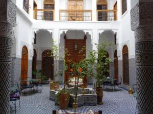 een binnenplaats in een gebouw met tafels en stoelen bij Dar Al Safadi in Fès