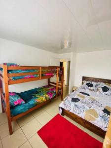sypialnia z 2 łóżkami piętrowymi i czerwonym dywanem w obiekcie Case Vi d' o' w mieście Le Tampon