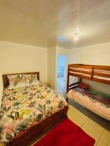 sypialnia z 2 łóżkami piętrowymi i czerwonym dywanem w obiekcie Case Vi d' o' w mieście Le Tampon