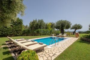 a swimming pool with lounge chairs next to a yard at Cote Jardin in Barbati