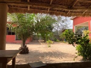 a courtyard with palm trees and a red building at CDAC Elijah - Espace Culturel in Ouidah
