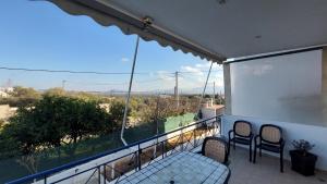 a balcony with two chairs and a large window at Makarios Apartment Near Athens Aiport in Spata