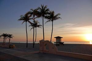 a sunset on the beach with palm trees and a bench at Beachside Luxury KING Suite in 4 Star Resort with Rooftop Bar and Pool in Hollywood
