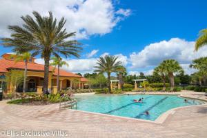 a swimming pool with palm trees and people in it at Casa Amore at Ellis Exclusive Villas in Davenport