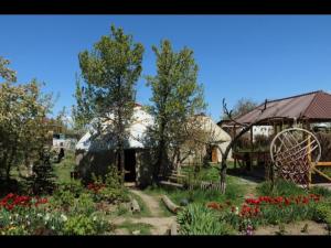 un jardín con flores y una noria en Karakol Yurts Camp en Karakol
