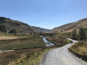 a dirt road through a valley with a river at The Stables in Tregaron