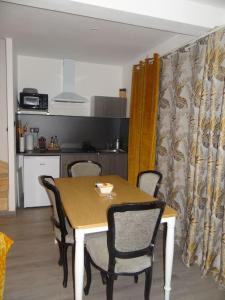a dining room table and chairs with a kitchen in the background at Cosy Loft - Appartement de charme in Marsannay-la-Côte