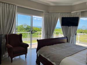 a bedroom with a bed and a chair and windows at Benri B&B & Self-Catering in Gonubie