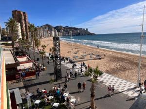 grupa ludzi spacerujących po plaży w obiekcie LUXURY front the BEACH PRINCIPADO w mieście Benidorm