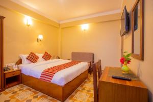 ein Hotelzimmer mit einem Bett und einem Schreibtisch in der Unterkunft Hotel Liberty Pokhara in Pokhara