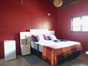 Pipa Zen Guest House في بيبا: غرفة نوم بجدران حمراء وسرير ونافذة