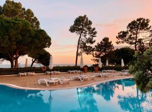 a swimming pool with white chairs and a resort at PortoBay Falesia in Albufeira