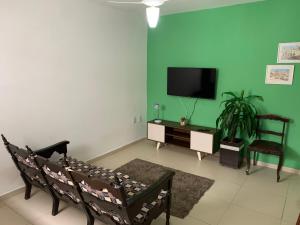 uma sala de estar com uma parede verde e uma televisão em Aloha Beach Temporada em Cabo Frio