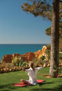 a woman sitting on a red blanket on the grass at PortoBay Falesia in Albufeira