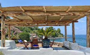 a wooden pergola with a table and chairs and the ocean at Nelinda Waterfront Accommodation in Ischia