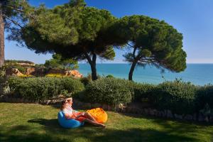 a woman sitting on an inflatable ball in the grass at PortoBay Falesia in Albufeira
