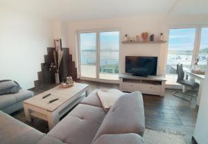 sala de estar con sofá y TV en Moderne Ferienwohnung mit Balkon direkt an der Peene, en Ziemitz