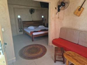 1 Schlafzimmer mit 2 Betten und einem roten Sofa in der Unterkunft LE KABOSS in Toliara