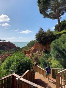 a woman walking down a wooden stairs near the ocean at PortoBay Falesia in Albufeira