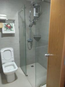 a bathroom with a toilet and a glass shower at Antara Residential Condominium in Talisay