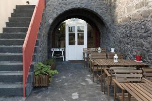 a restaurant with wooden tables and a stone wall at Azorean Urban Lodge in Ponta Delgada