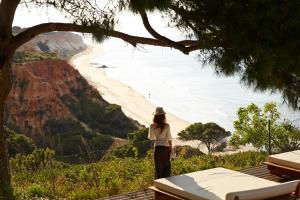 a woman standing on a hill looking at the beach at PortoBay Falesia in Albufeira