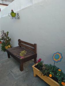 un banco de madera sentado junto a una pared blanca con flores en La estacion en Tandil