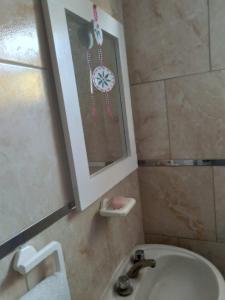 een badkamer met een wastafel, een spiegel en een klok bij La estacion in Tandil