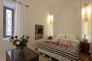 ein Schlafzimmer mit einem Bett mit einem Tisch und einer Vase aus Blumen in der Unterkunft Riad Jenan L'mouassine in Marrakesch